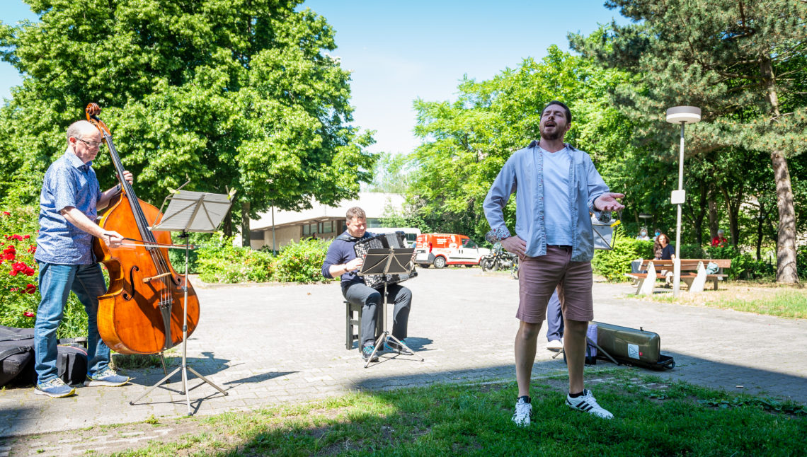 Ein Mann singt begleitet von einem Musikanten-Trio auf der Straße.