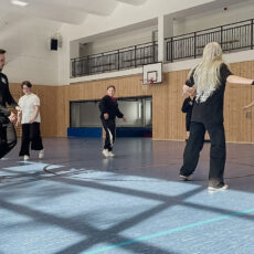 Sechs Jugendliche, die in einer Turnhalle an einem Breakdance-Training teilnehmen.