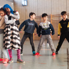 Eine Gruppe an Kindern tanzt in einer Sporthalle