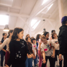 Viele Kinder schauen der Trainerin beim Tanzen zu.